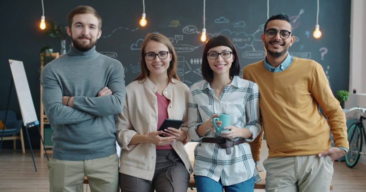 Quatre jeunes adultes souriants dans un espace de travail collaboratif — emplois d'été Canada OBNL